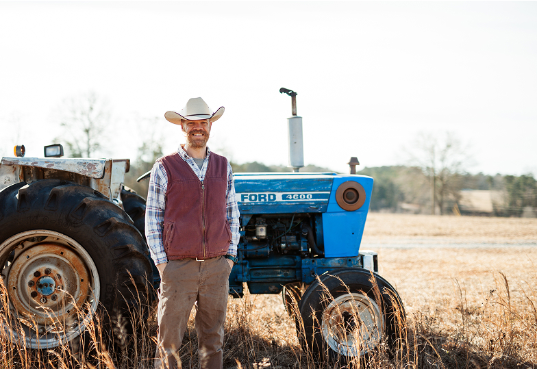 Wesley standing beside a Ford 4600 tractor in a field